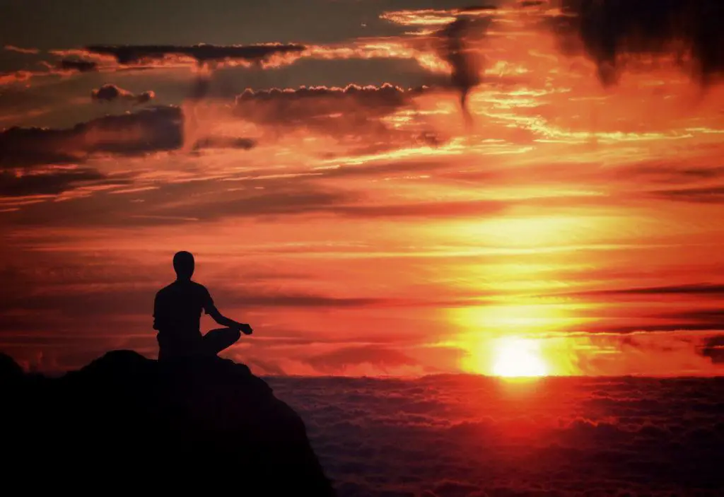 A person practicing meditation in a calm, natural setting